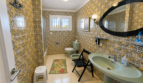 Geräumiges Badezimmer der Mallorca-Villa mit grüner Sanitärausstattung und charakteristischen Mosaikfliesen in Gold-Weiß