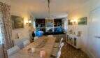 Helles Wohn-Esszimmer der Mallorca-Villa in Llucmajor mit Holztisch, Bücherregal und gemustertem Originalboden.