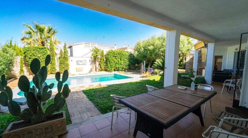 Überdachte Terrasse mit Esstisch, Pool und üppigem Garten der Villa in Llucmajor, Mallorca