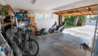 Geräumige Garage der Mallorca-Villa in Llucmajor mit Motorroller, Fahrrad, Rasenmäher und Regalen, direkter Ausgang zum Freien.