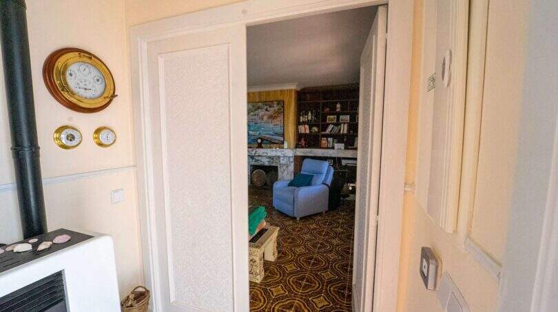 Durchgang zum Wohnzimmer mit Kamin, Bücherregal und gemustertem Teppich in mallorquinischer Villa