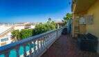 Balkon der Mallorca-Villa in Llucmajor mit weißem Geländer, Blick auf Pool und begrünten Garten