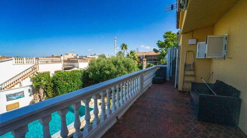 Balkon der Mallorca-Villa in Llucmajor mit weißem Geländer, Blick auf Pool und begrünten Garten