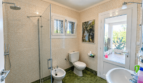 Helles Badezimmer der Mallorca-Villa mit Glasdusche, Bidet, WC und Gartenblick durch Glastür.