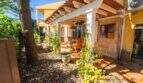Überdachte Terrasse mit Holzmöbeln und begrüntem Garten der Villa in Llucmajor, Mallorca