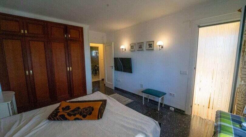 Geräumiges Schlafzimmer der Mallorca-Villa mit Holzeinbauschrank, Flachbild-TV und Zugang zur Terrasse