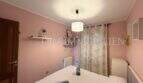 Schlafzimmer mit rosa Wänden, Doppelbett, Pendelleuchte und Fenster mit Vorhang im Ferienhaus Muro