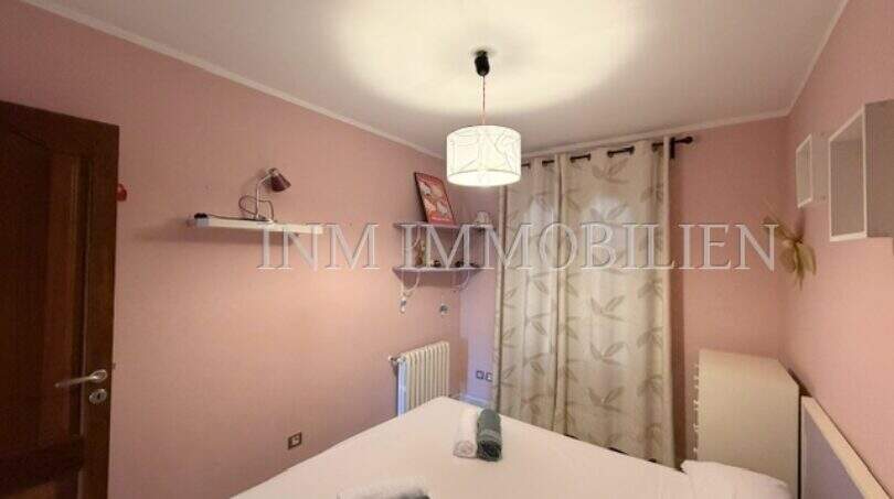 Schlafzimmer mit rosa Wänden, Doppelbett, Pendelleuchte und Fenster mit Vorhang im Ferienhaus Muro
