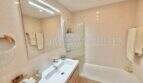 Modernes Badezimmer mit Wanne, Waschtisch und hellen Fliesen in Wohnung in Palmanova