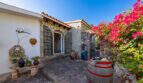 Rustic entrance area of the sea view villa in Cala Murada with stone walls, wooden barrel and bougainvillea.
