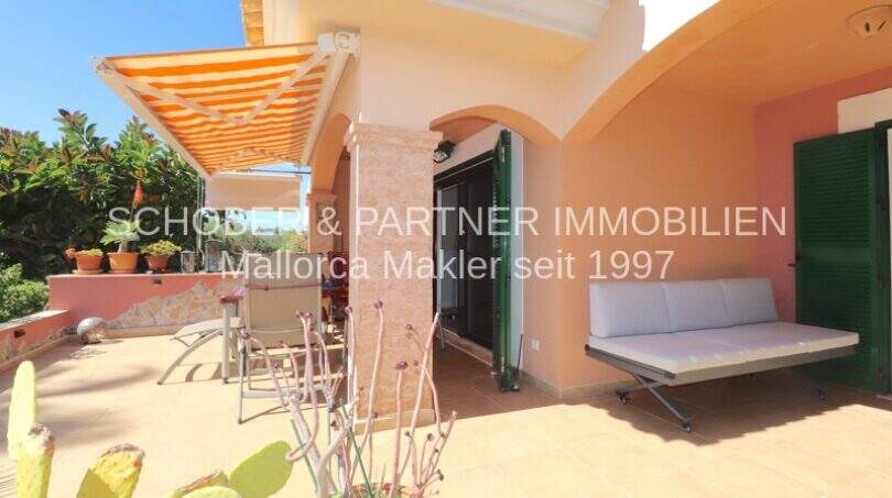 Terraza soleada con sofá lounge, toldo y cactus del apartamento de 4 habitaciones en Cala Millor