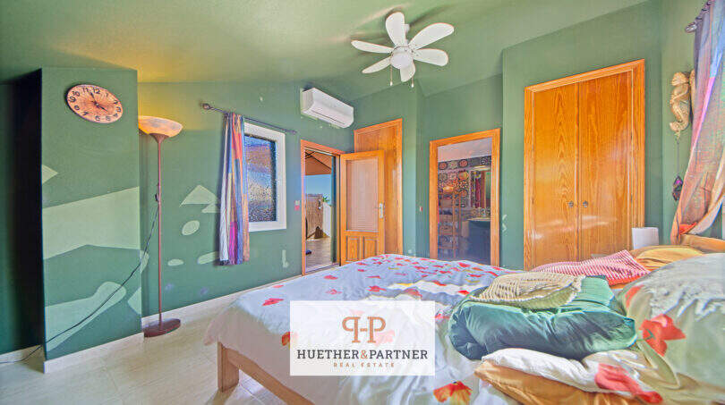 Schlafzimmer mit grünen Wänden, Doppelbett, Deckenventilator, Klimaanlage und Einbauschrank in Cala Murada