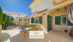 Sonnige Terrasse mit Picknicktisch, Sonnenschirm und Pool eines charmanten Hauses in Cala Murada.