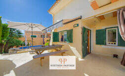 Sonnige Terrasse mit Picknicktisch, Sonnenschirm und Pool eines charmanten Hauses in Cala Murada.