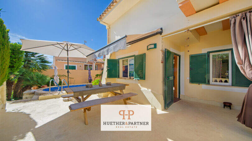 Sonnige Terrasse mit Picknicktisch, Sonnenschirm und Pool eines charmanten Hauses in Cala Murada.