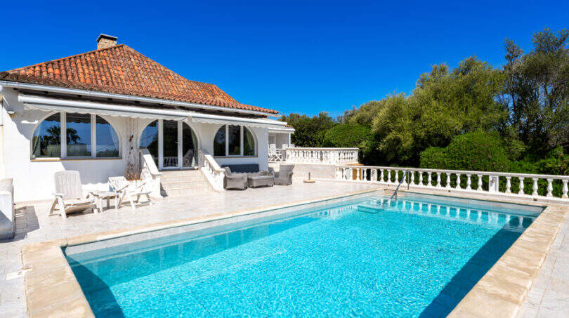Außenpool mit Terrasse und weißer Villa mit Terrakotta-Dach in Cala Murada, umgeben von Grün