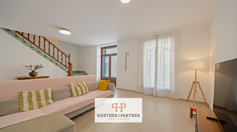 Helles Wohnzimmer mit Sofa, Holztreppe und Terrassentür im Stadthaus Manacor