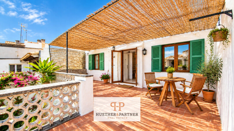 Sonnige Dachterrasse mit Bambus-Pergola, Holzmöbeln und grünen Fensterläden im Stadthaus Manacor