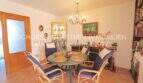 Helles Esszimmer mit rundem Tisch, Rattanstühlen, Vitrine und Bücherregal im Chalet Sa Coma