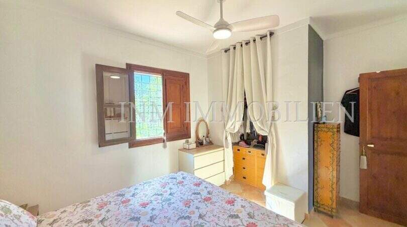Schlafzimmer der mediterranen Finca bei Algaida mit Deckenventilator, Holzfenster und Kleiderschrank.