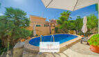 Ovaler Pool mit Natursteinumrandung, Sonnenschirme und mediterraner Bepflanzung am Ferienhaus in Cala Murada