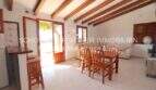 Bright living-dining room of the Mallorca finca with wooden beam ceiling, dining table and terrace access to the garden.