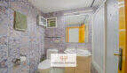 Badezimmer mit gemusterten Fliesen, Waschbecken, WC und Dusche im Haus mit Pool und Meerblick in Cala Murada