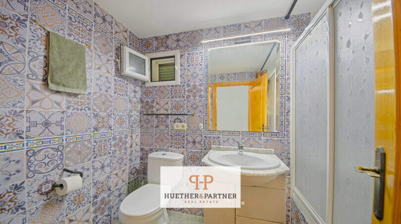 Badezimmer mit gemusterten Fliesen, Waschbecken, WC und Dusche im Haus mit Pool und Meerblick in Cala Murada