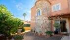 Außenansicht Chalet Sa Coma: Mediterrane Villa mit Natursteinturm, Terrasse und tropischem Garten, meernahe Lage.