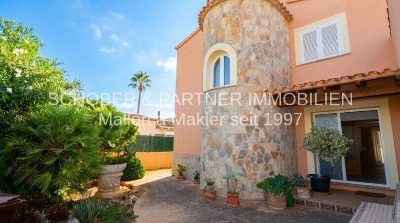 Außenansicht Chalet Sa Coma: Mediterrane Villa mit Natursteinturm, Terrasse und tropischem Garten, meernahe Lage.