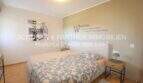 Dormitorio claro con cama doble, lema decorativo en la pared e impresión de arte de Londres en apartamento en Cala Millor