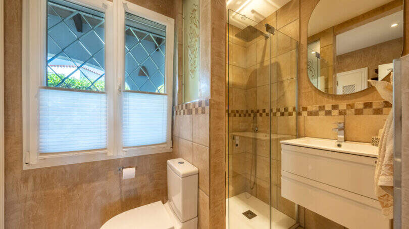 Elegant bathroom of the sea view villa in Cala Murada with glass shower, washbasin and decorative leaded glass window.
