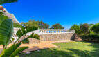 Gepflegter Garten mit Terrasse, Steinmauer, weißem Balustradenzaun und tropischer Bepflanzung der Villa in Cala Murada