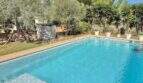 Privater Pool der mediterranen Finca bei Algaida, umgeben von Olivenbäumen, Palmen und gepflegten Gartenanlagen.