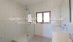 Bright bathroom of the Mallorca finca with walk-in glass shower, modern sink and small window.