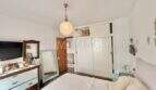 Dormitorio luminoso con cama doble, cómoda de madera, espejo y armario empotrado en casa mediterránea en Sa Ràpita.