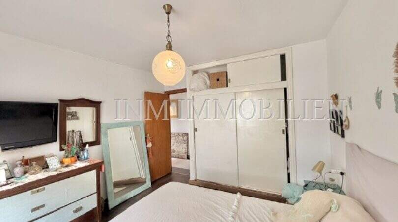 Dormitorio luminoso con cama doble, cómoda de madera, espejo y armario empotrado en casa mediterránea en Sa Ràpita.
