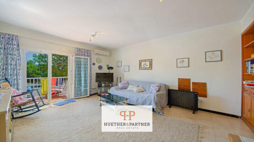 Luminoso salón del apartamento vacacional Porto Cristo con acceso al balcón, sofá, TV y vistas al mar