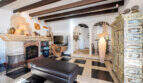 Living room of the sea view villa with fireplace, wooden beam ceiling, checkered floor and antique wooden cabinet in Cala Murada