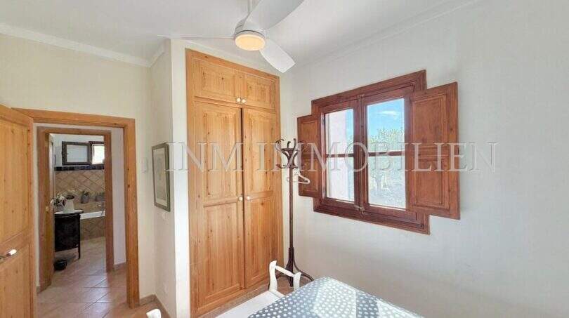 Schlafzimmer der Finca Algaida mit Holzschrank, Deckenventilator, Terrakottaboden und Fenster mit Holzläden