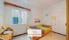 Luminoso dormitorio con cama individual, muebles de madera y ventana con vistas al mar en apartamento Porto Cristo