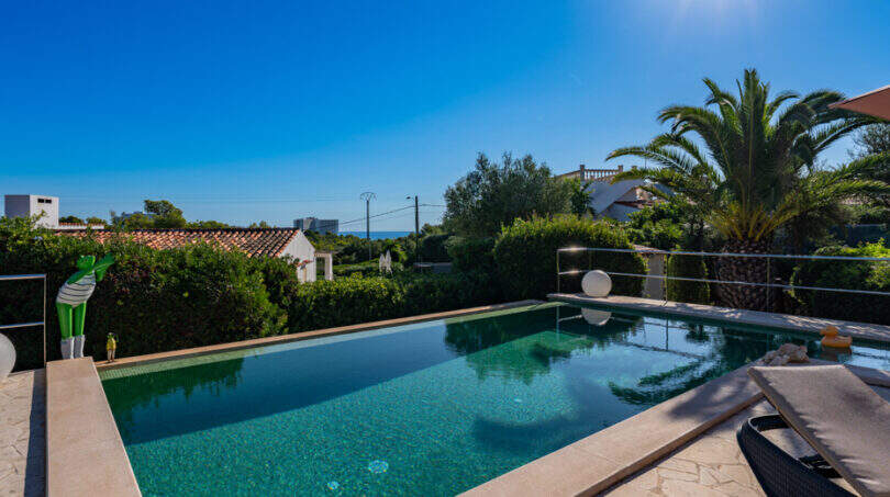 Infinity pool with turquoise water, palm trees and sea view of the villa in Cala Murada