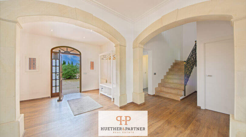 Heller Eingangsbereich der Finca Santa Maria mit Natursteinbögen, Holzdielenboden und elegantem Treppenaufgang.