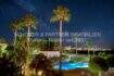 Vista nocturna de la piscina iluminada con palmeras y cielo estrellado, complejo de apartamento de 4 habitaciones en Cala Millor.