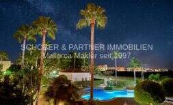 Vista nocturna de la piscina iluminada con palmeras y cielo estrellado, complejo de apartamento de 4 habitaciones en Cala Millor.