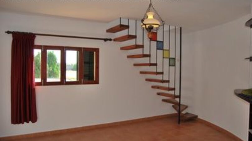 Helles Wohnzimmer der Finca Manacor mit Wendeltreppe, Terrakottaboden, Fenster und Hängelampe