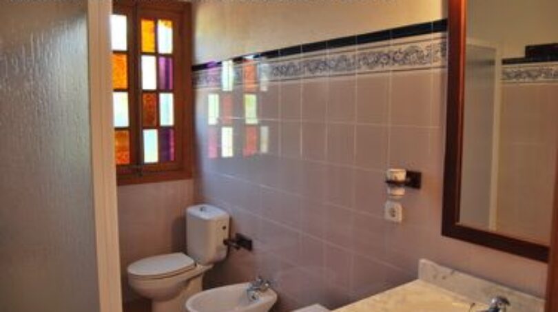 Badezimmer der Finca Manacor mit WC, Bidet, Waschbecken und farbigen Buntglasfenstern