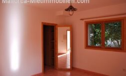 Helles Zimmer der Finca Manacor mit Terrakottaboden, Holzfenster und Blick in den Flur