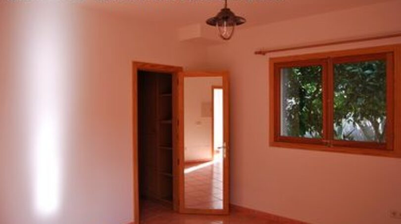 Helles Zimmer der Finca Manacor mit Terrakottaboden, Holzfenster und Blick in den Flur