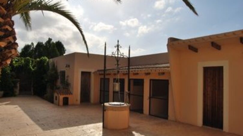 Gepflasterter Innenhof der Finca Manacor mit historischem Brunnen, mediterranen Nebengebäuden und Palme
